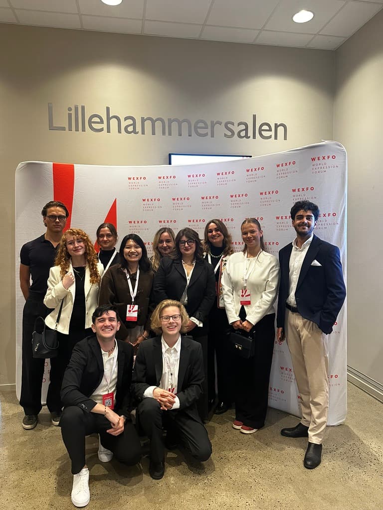 Justus August (left) with fellow debate participants in front of the World Expression Forum backdrop at WEXFO 2026, Lillehammer